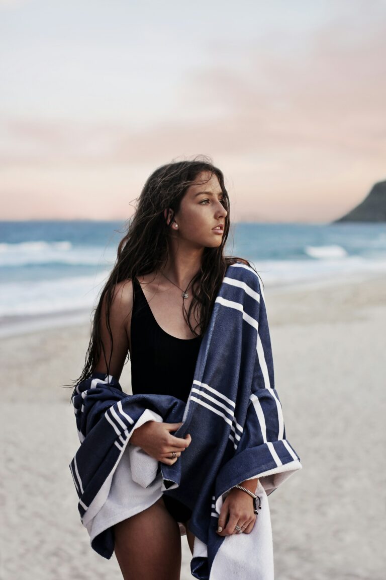 Beautiful women standing on the beach with a blue beach day cover.