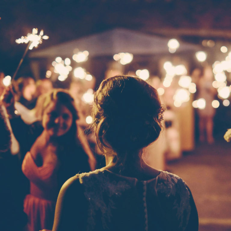 Women standing at an end-of-summer party with everyone holding sparklers.