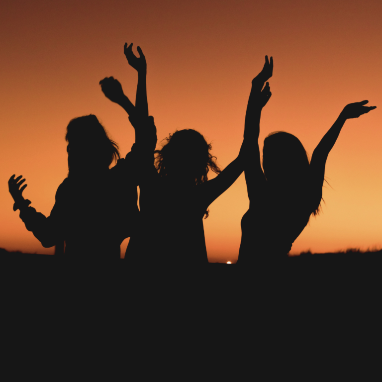 Three friends having fun as the summer sun sets during their end-of-summer party.