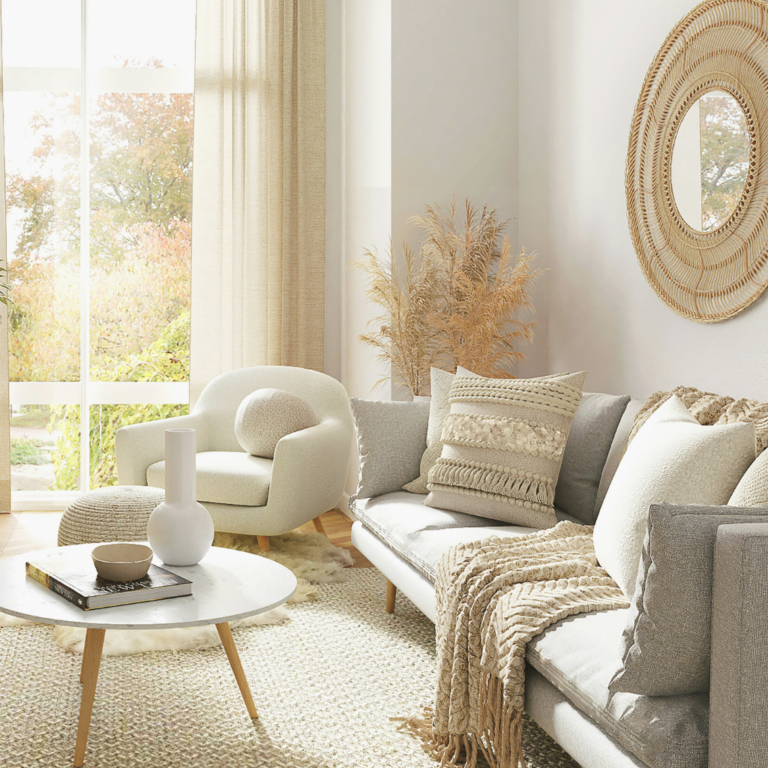 A beautiful living room set with a light couch, chair, coffee table, and mirror on the wall.